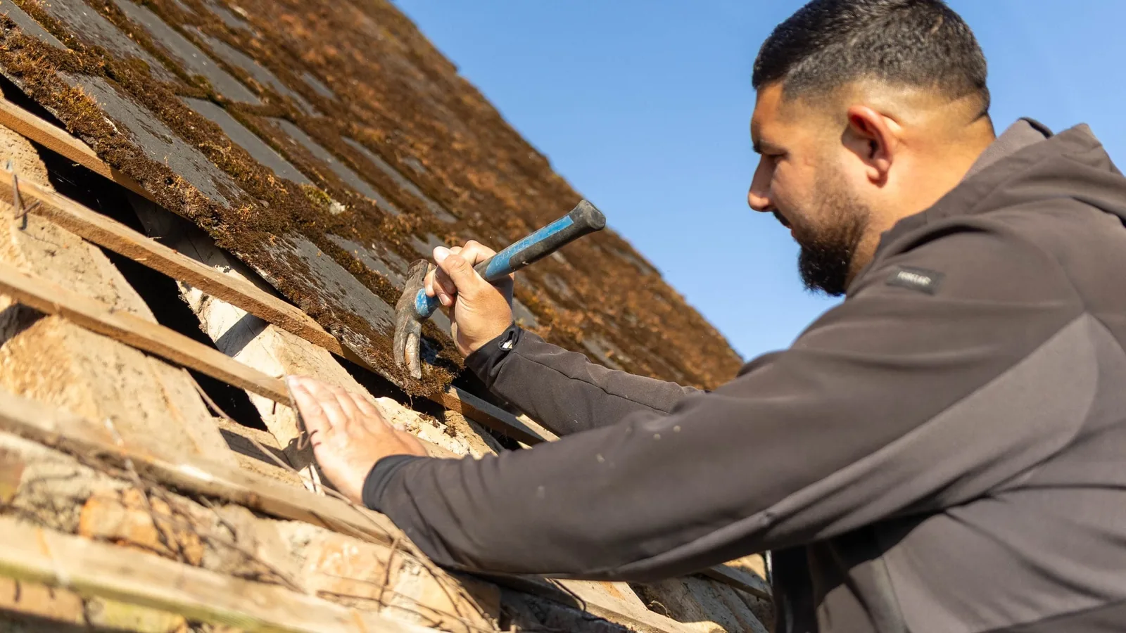 Charpentier KING RENOV travaillant au marteau sur des liteaux de toiture